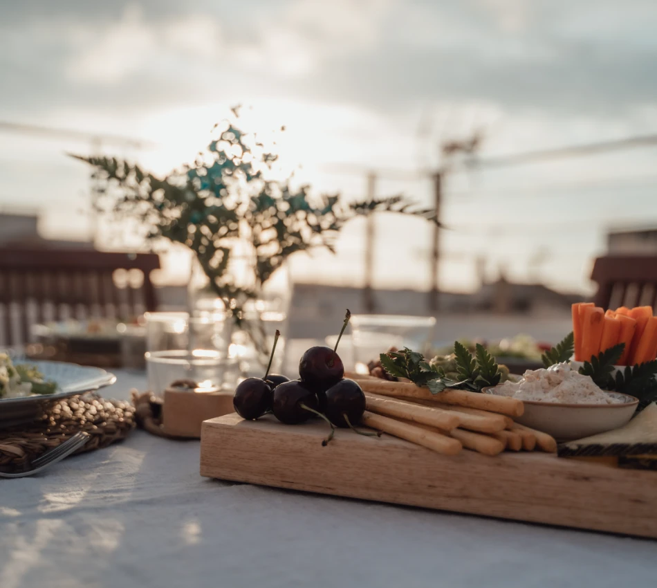 Tabla de aperitivos con verduras y cerezas al atardecer.