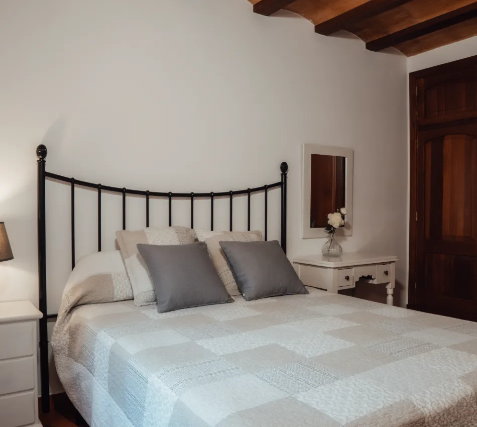 Dormitorio acogedor con cama de hierro y l&aacute;mpara de noche.