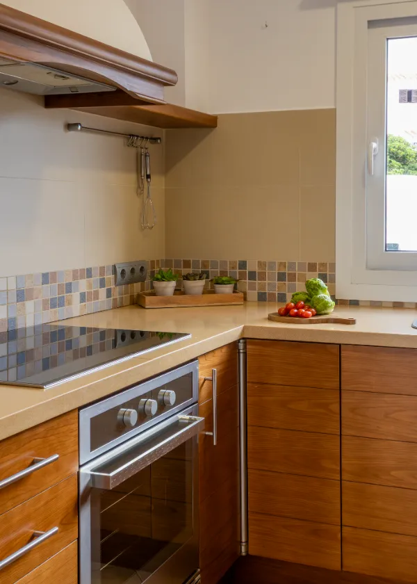 Cocina moderna con encimeras de madera, horno y verduras frescas en la esquina.
