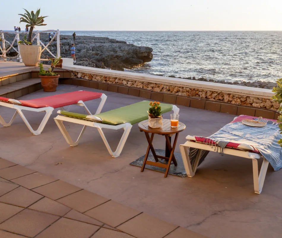 Tumbonas y mesa junto al mar al atardecer.