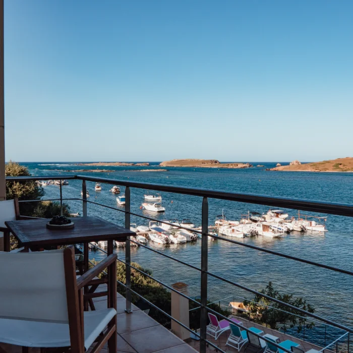 Vista desde un balc&oacute;n hacia el mar con barcos anclados bajo un cielo claro.