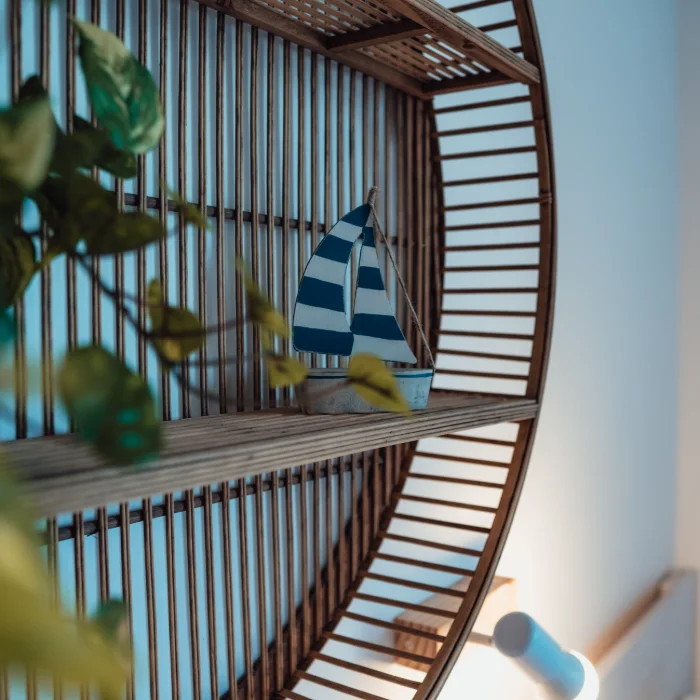 Estante circular de madera con velero en miniatura y planta decorativa.