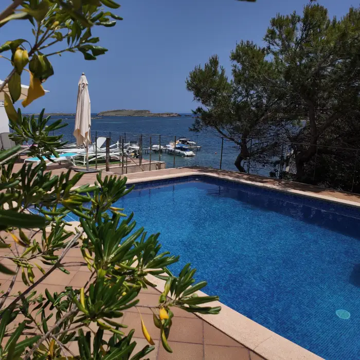 Piscina junto al mar, rodeada de &aacute;rboles y peque&ntilde;as embarcaciones.