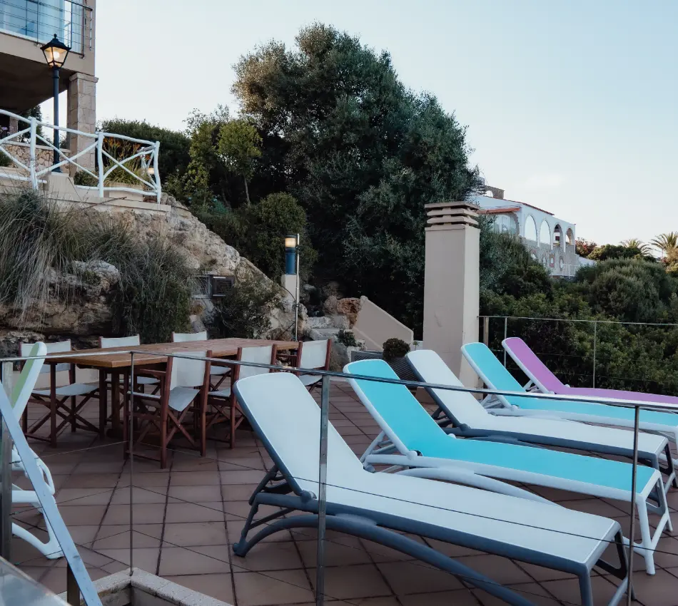 Terraza con tumbonas coloridas y una mesa de madera al aire libre.