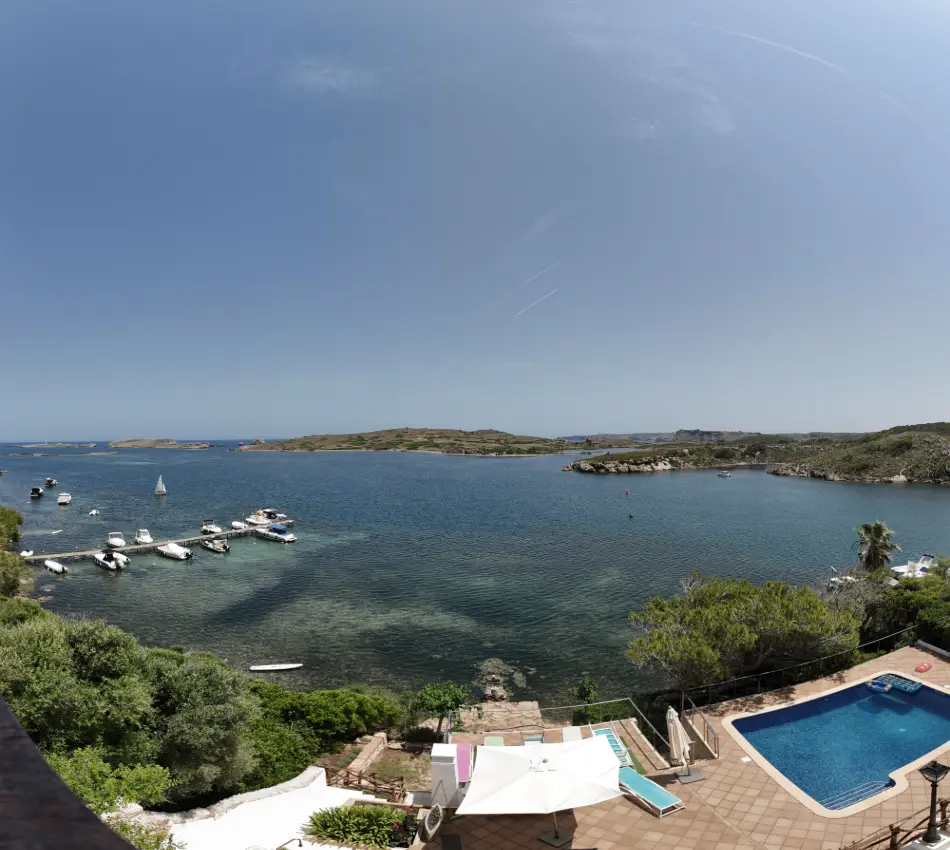 Vista a&eacute;rea de una bah&iacute;a con botes, piscina y paisaje natural alrededor.