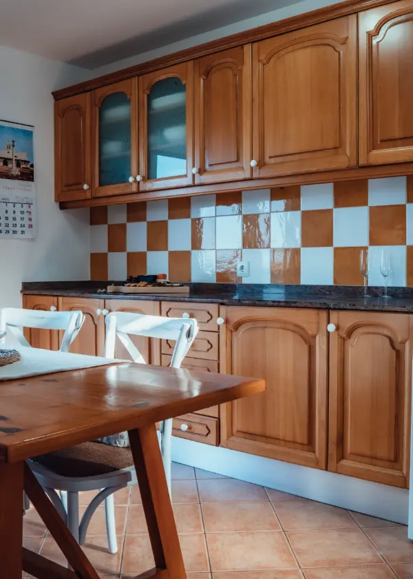 Cocina con muebles de madera y azulejos blancos y naranjas.