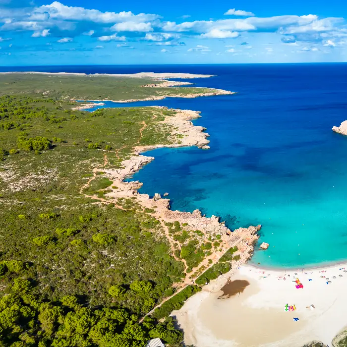 Costa con playa de arena blanca y agua turquesa vista desde arriba.