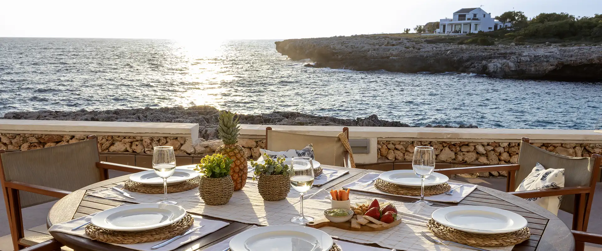 Mesa al aire libre con vista al mar y comida al atardecer.