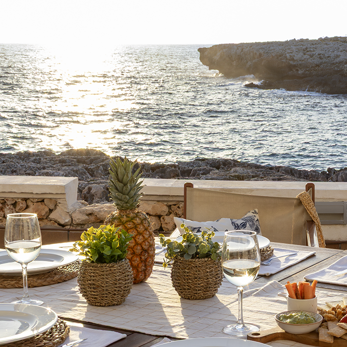 Mesa con decoraci&oacute;n y vista al mar al atardecer.