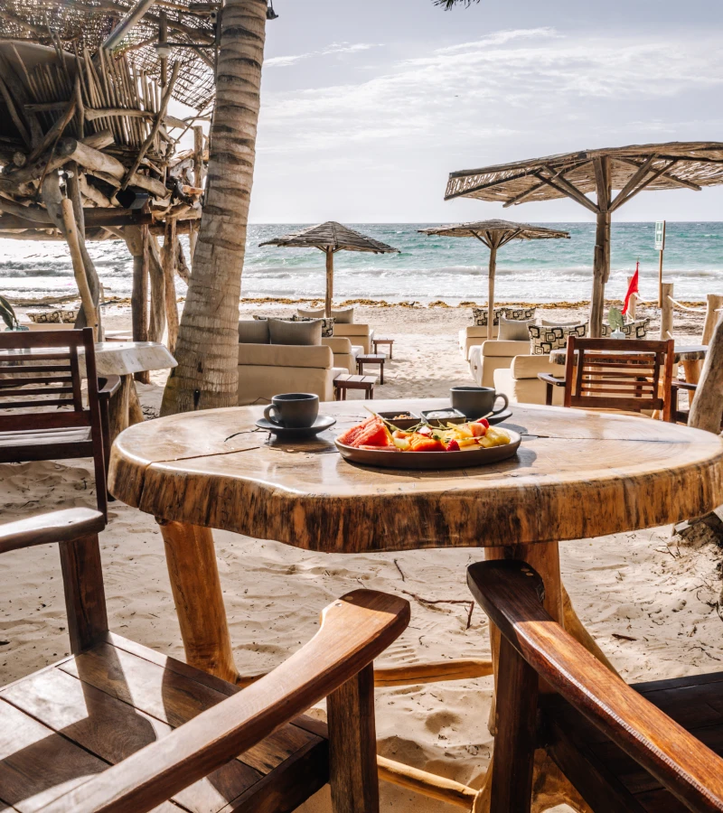 Beachside table with fruit, coffee, and ocean view.