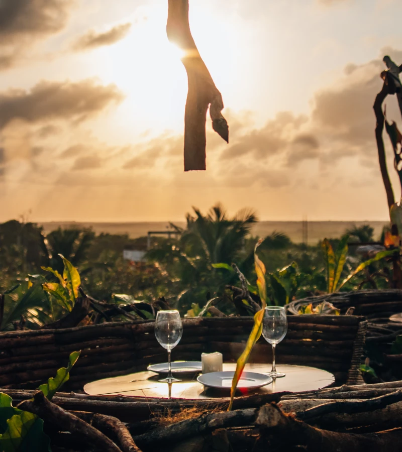 Outdoor table set for two, with sunset in the background.