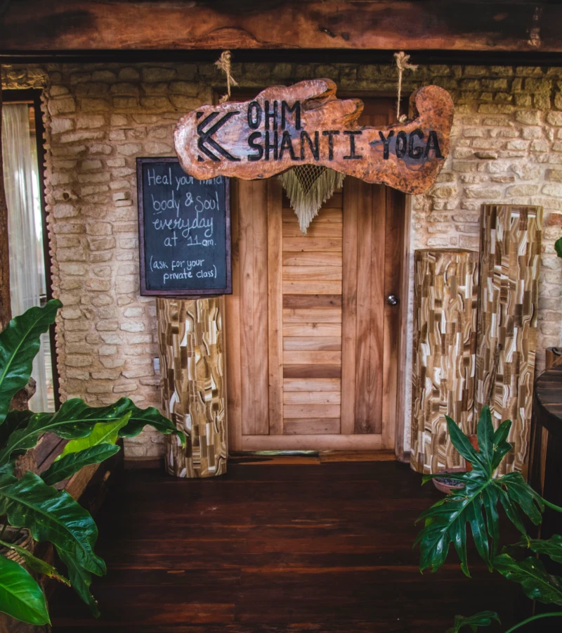 Yoga studio entrance with wooden sign and plants.
