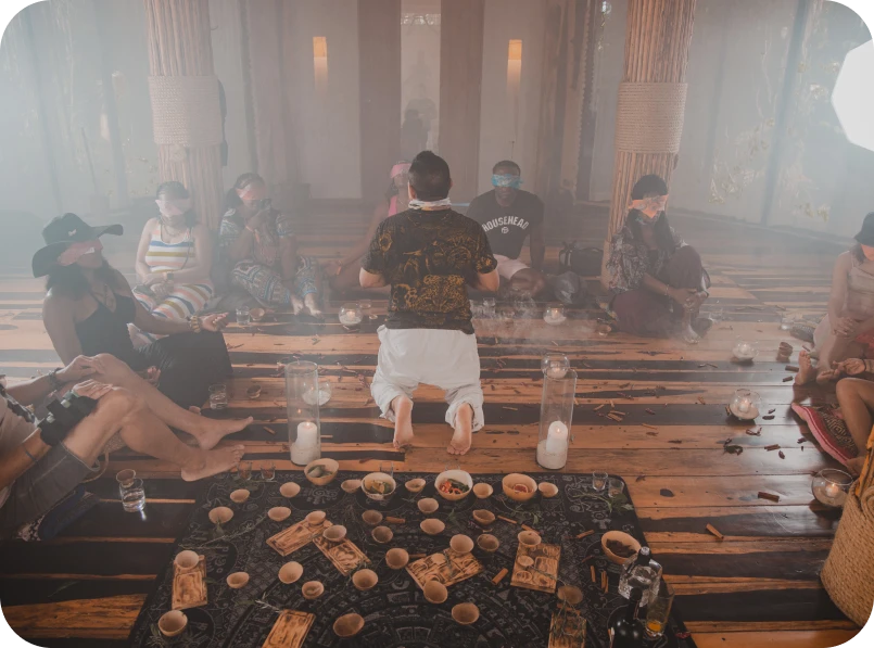 People sitting in a circle during a ceremony with candles and small bowls.