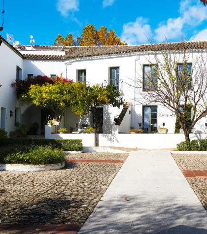 Casa blanca con jard&iacute;n y cielo azul.