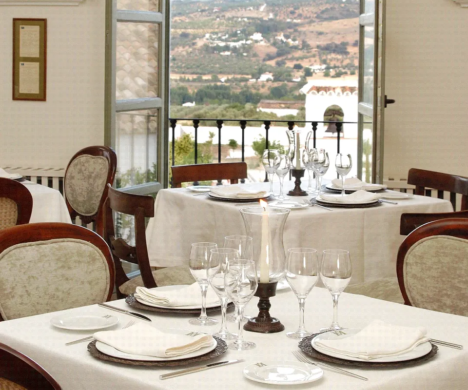 Comedor elegante con mesa puesta y vistas a un paisaje monta&ntilde;oso.