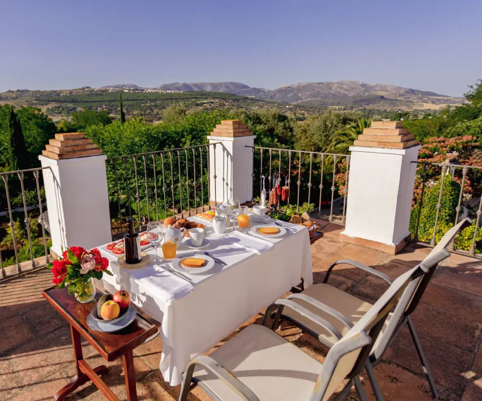 Mesa con desayuno en terraza con vista a monta&ntilde;as.
