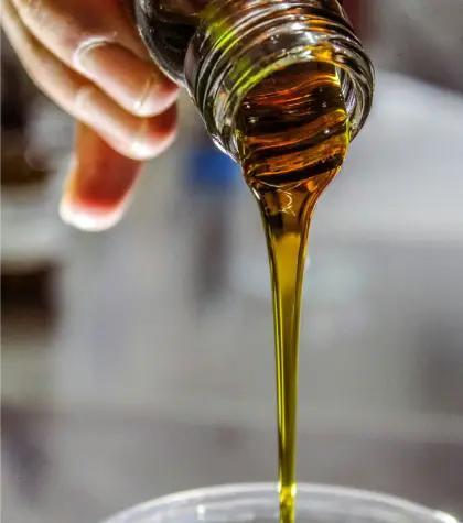 Aceite verti&eacute;ndose de una botella sobre una superficie transparente.