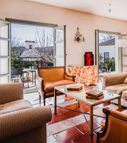 Sala de estar luminosa con muebles cl&aacute;sicos y vistas al jard&iacute;n exterior.