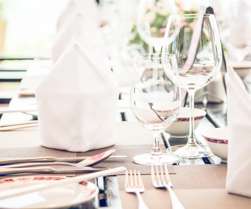 Mesa elegante con copas, cubiertos y servilletas blancas plegadas.