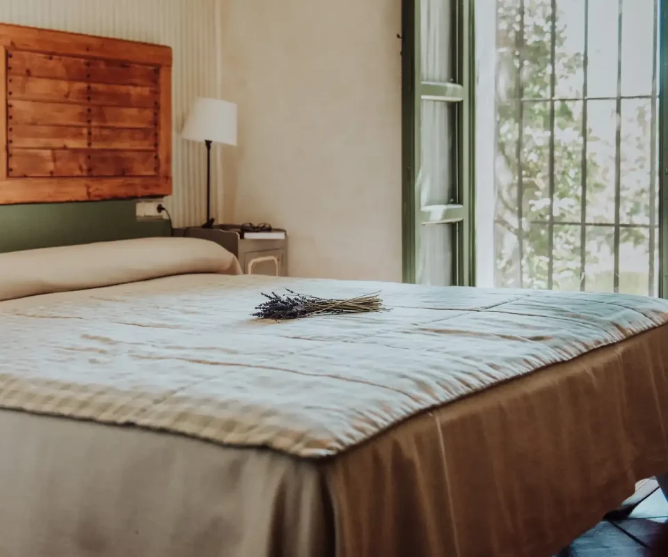 Habitaci&oacute;n luminosa con cama y ventana abierta al jard&iacute;n.