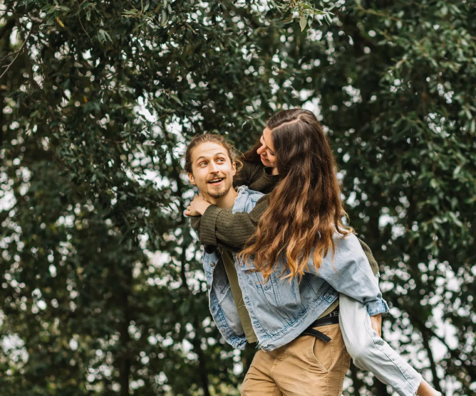 Pareja joven divirti&eacute;ndose en un parque bajo &aacute;rboles.