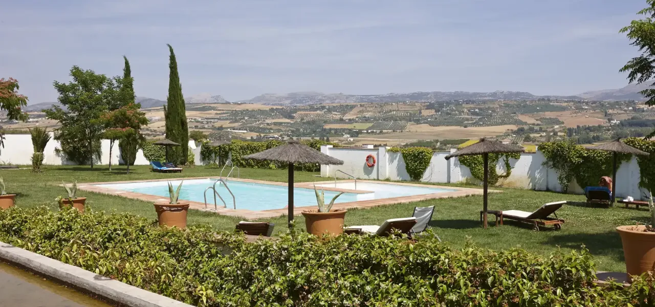 Piscina en un jard&iacute;n con vistas panor&aacute;micas al campo y monta&ntilde;as.