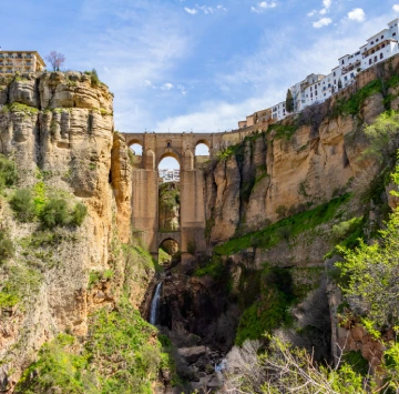 Puente de piedra en un impresionante desfiladero con casas en el borde.