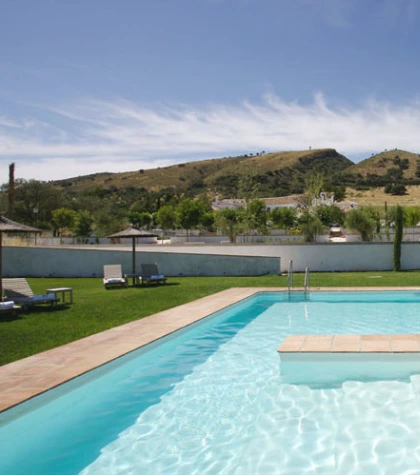 Piscina al aire libre con colinas de fondo en un d&iacute;a soleado.