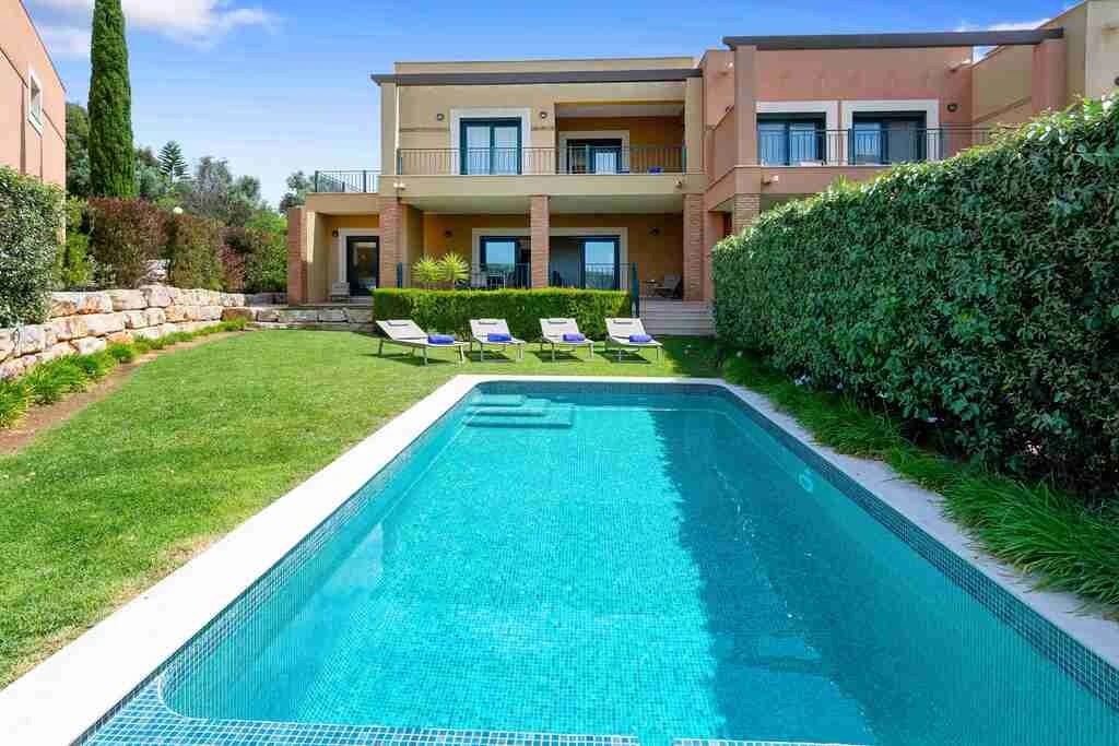 Modern villa with a pool, garden, and lounge chairs.
