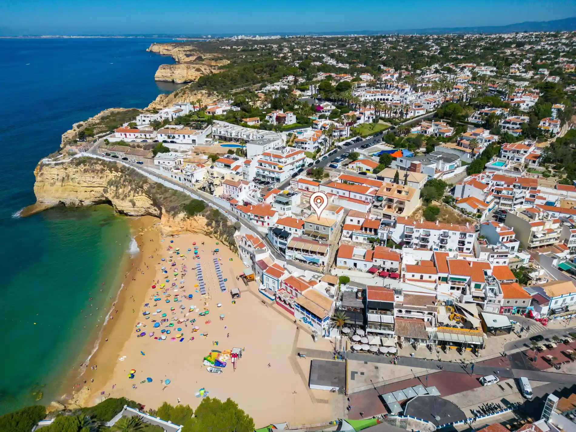 Coastal village with cliffside beach and colorful umbrellas.