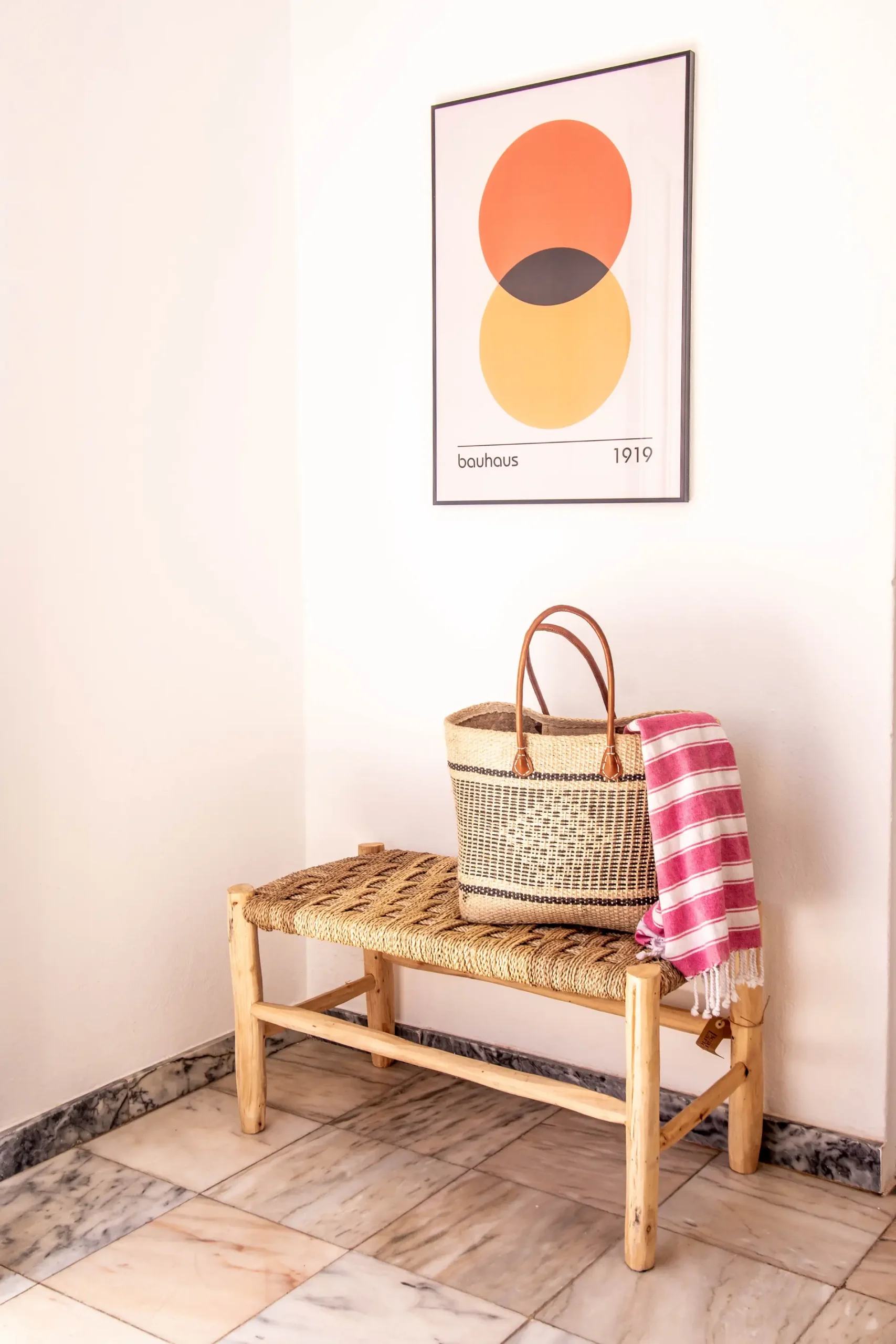 Bauhaus print over a bench with a basket and pink towel in a corner.