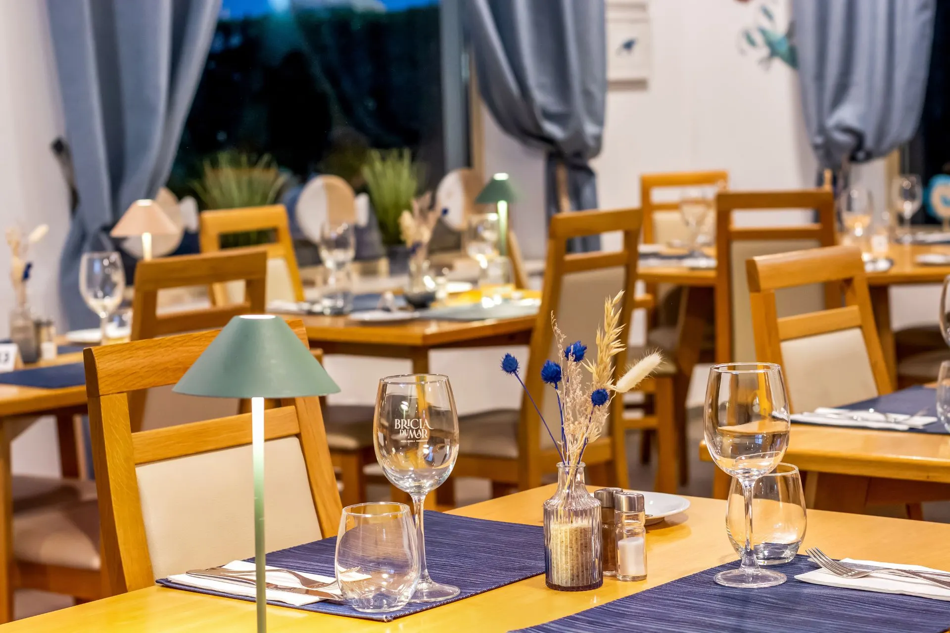 Cozy restaurant with set tables, blue decor, and wooden chairs.
