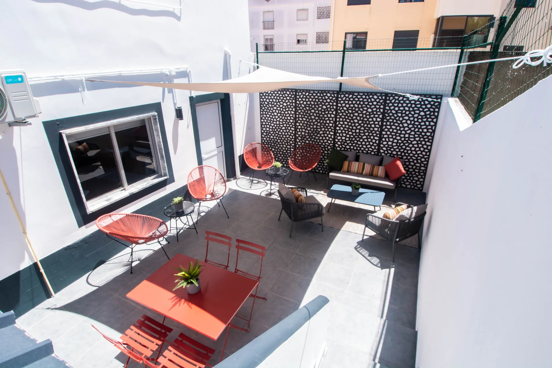 Outdoor patio with modern chairs, tables, and shade canopy.
