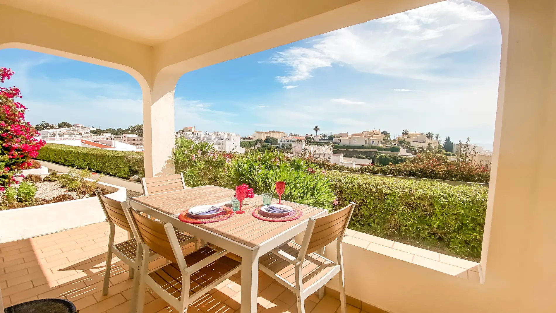 Sunny patio with dining table overlooking a scenic hillside village.