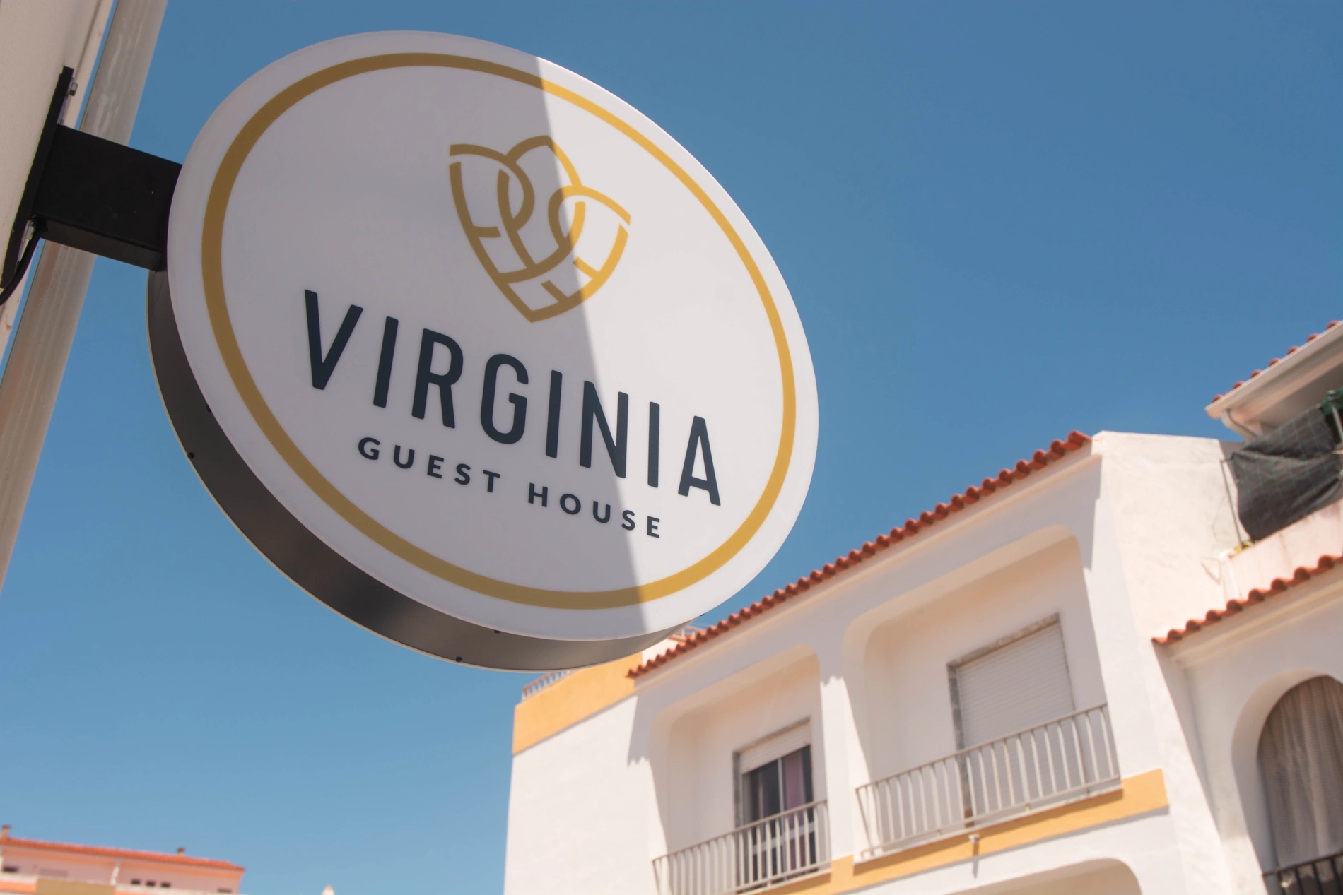 Sign for Virginia Guest House against a clear blue sky.