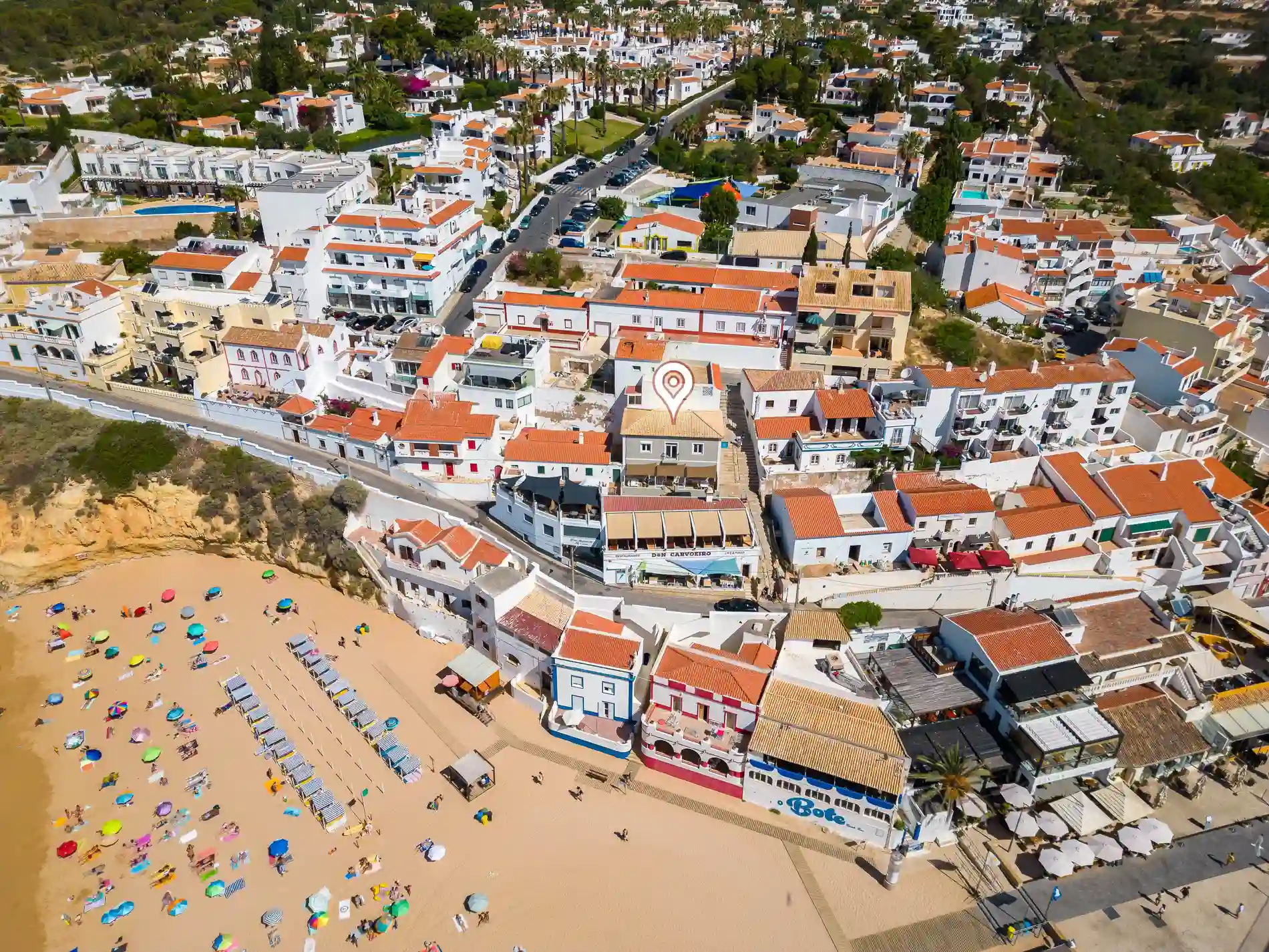 Aerial view of a beach and a town with white buildings and orange roofs.