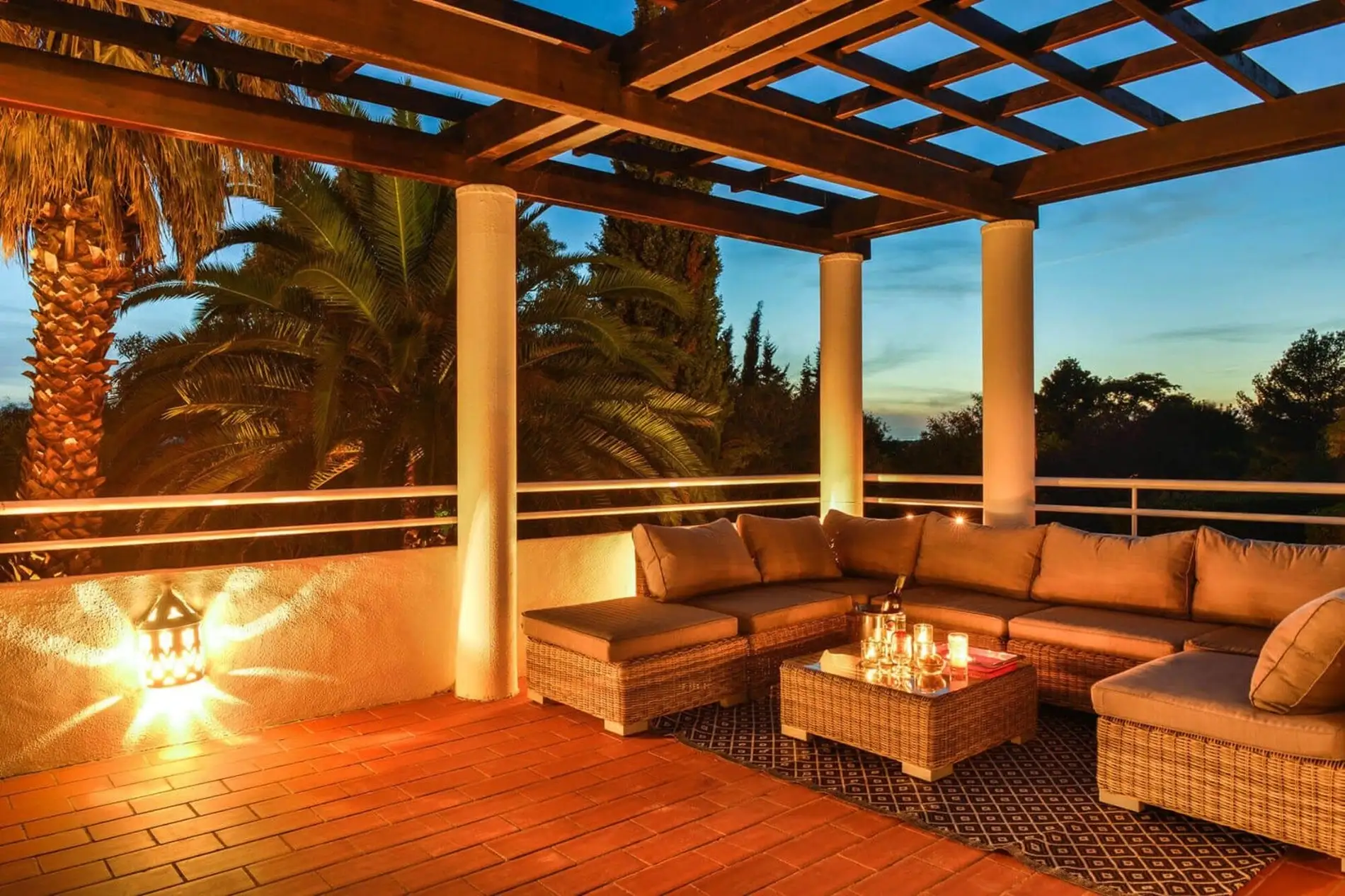 Outdoor patio with comfy seating, lantern light, and evening sky.