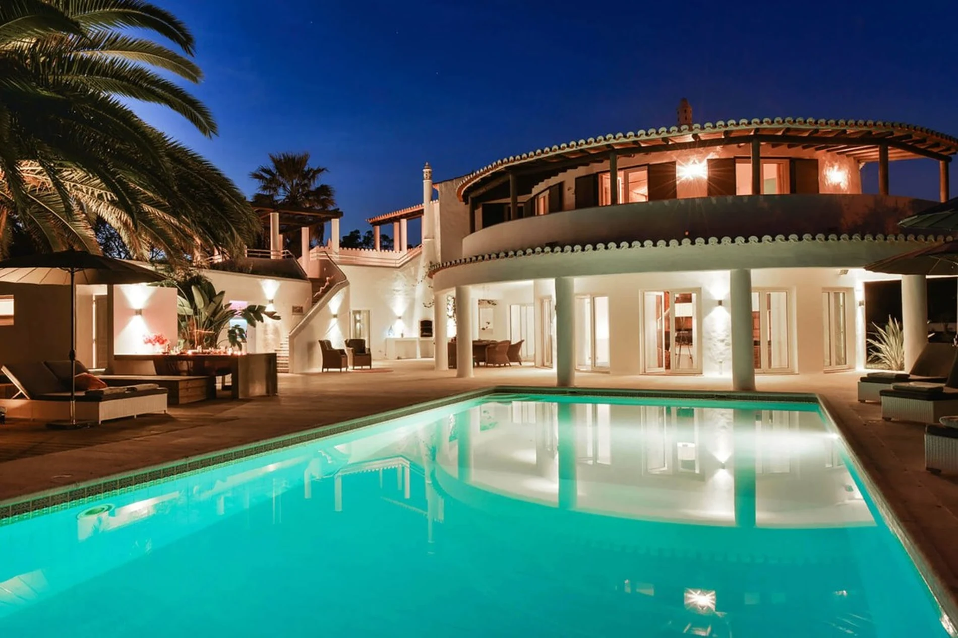 Luxurious villa with a pool, lit at night.
