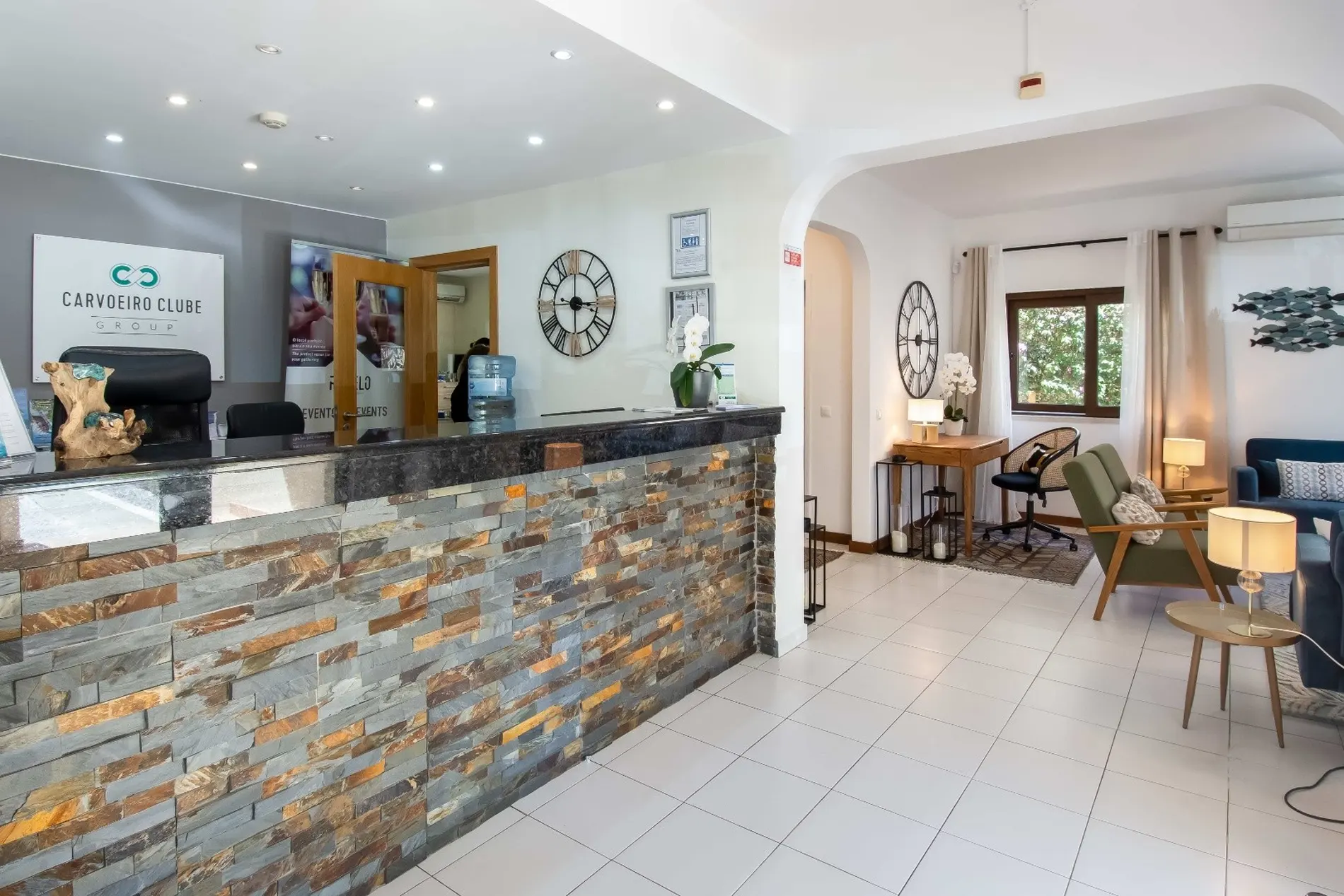 Reception area with a stone-front desk and a seating area in the background.
