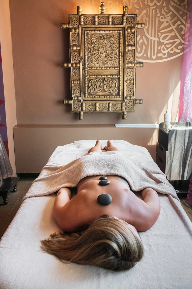 Person receiving hot stone therapy on a massage table.