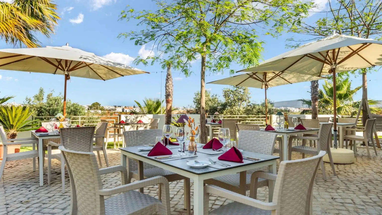 Outdoor patio dining with umbrellas and set tables on a sunny day.