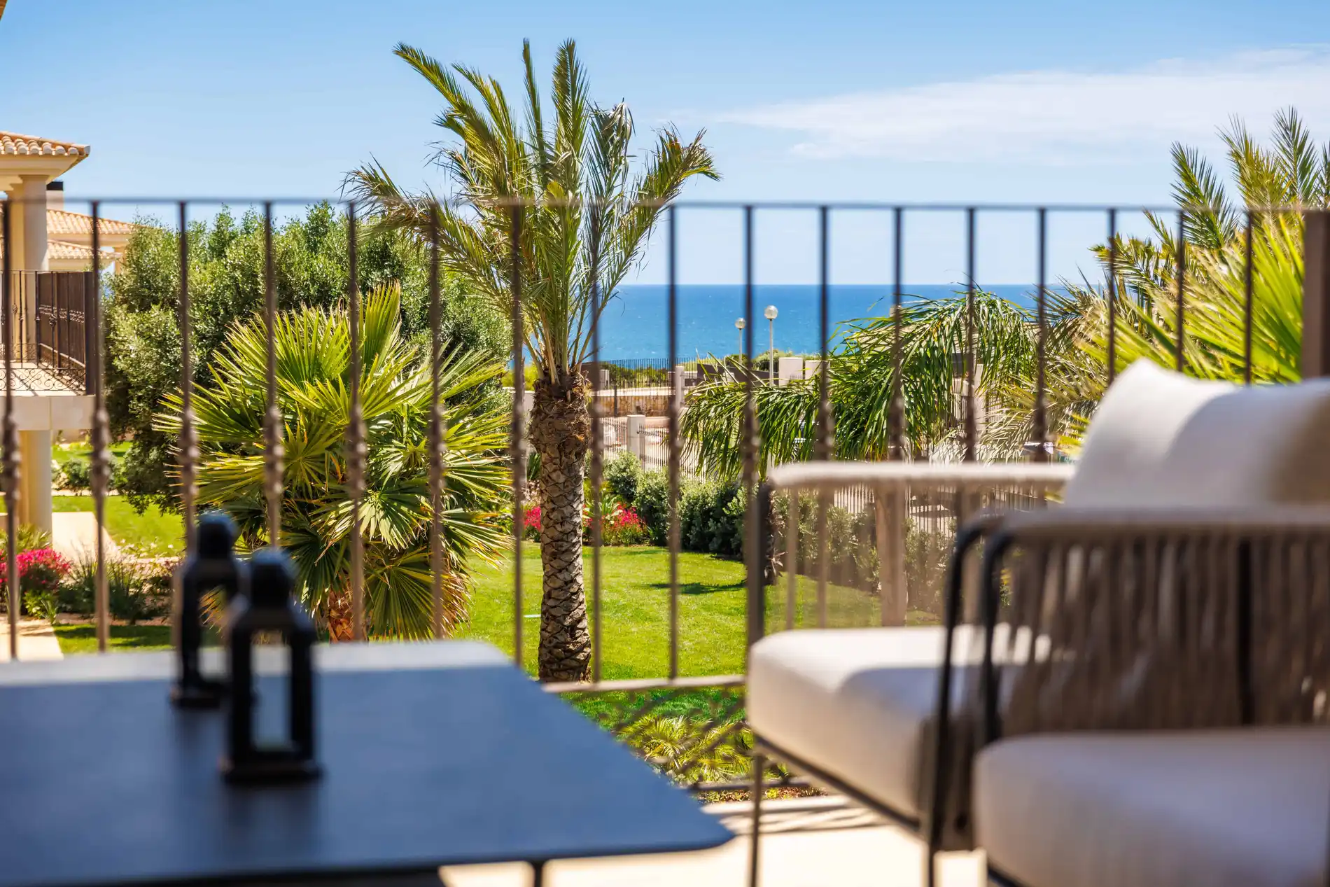 Balcony view of palm trees, garden, and ocean.