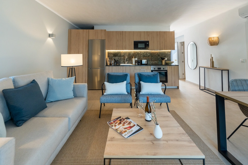 Modern living room and kitchen with blue accents and wooden furniture.