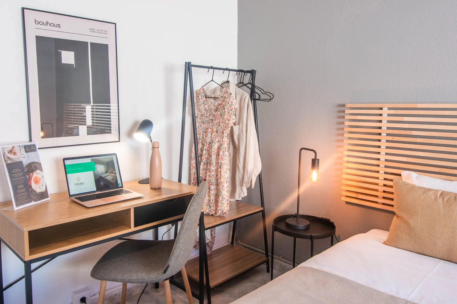 Cozy room with desk, laptop, clothes rack, and bed.