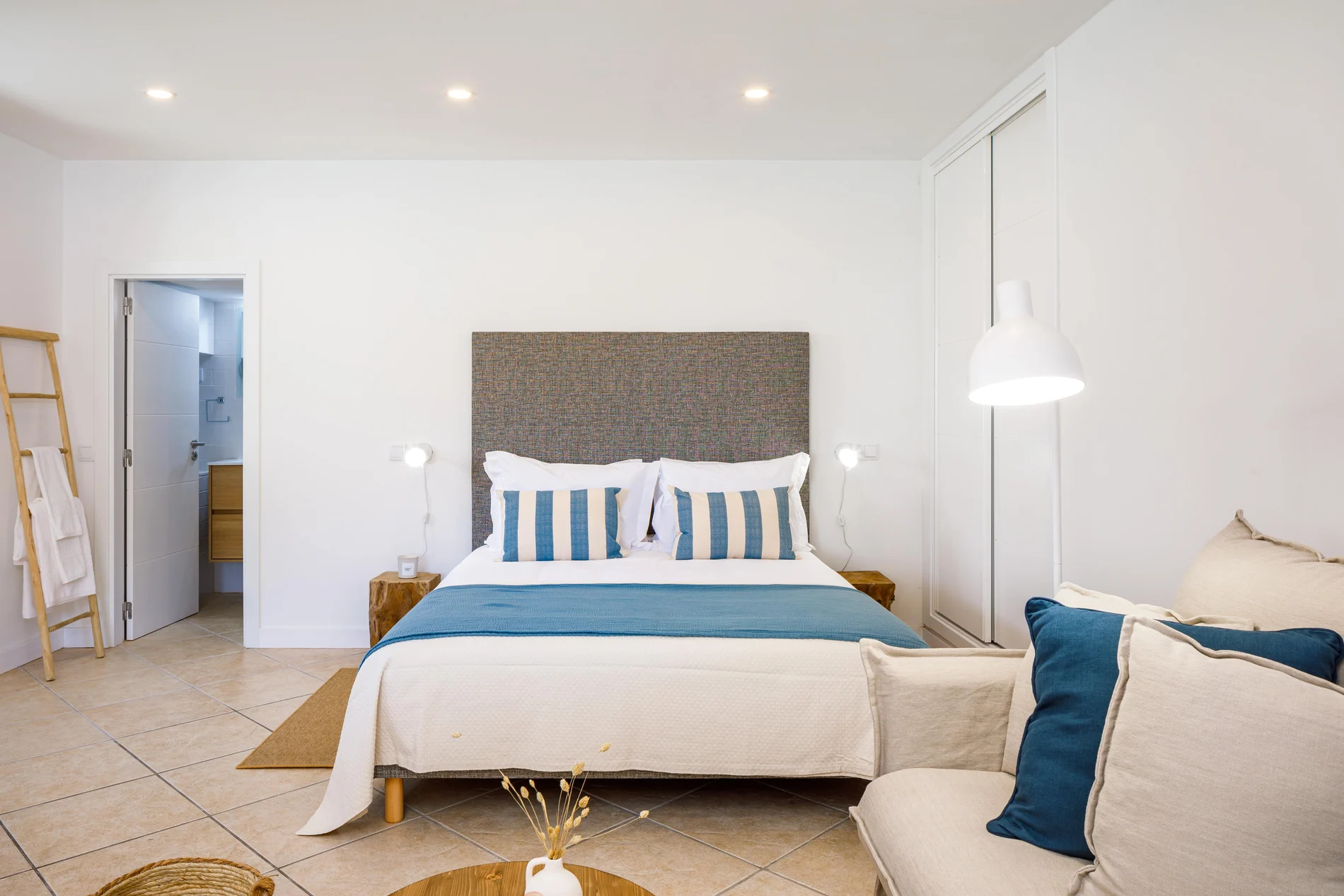 Modern bedroom with blue accents and cozy seating area.