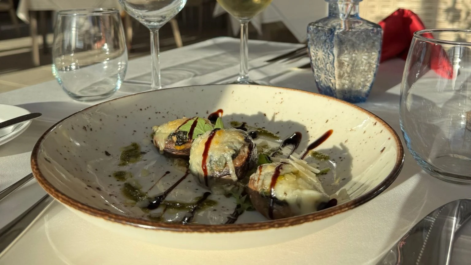 Plate of stuffed mushrooms with balsamic drizzle on a table setting.