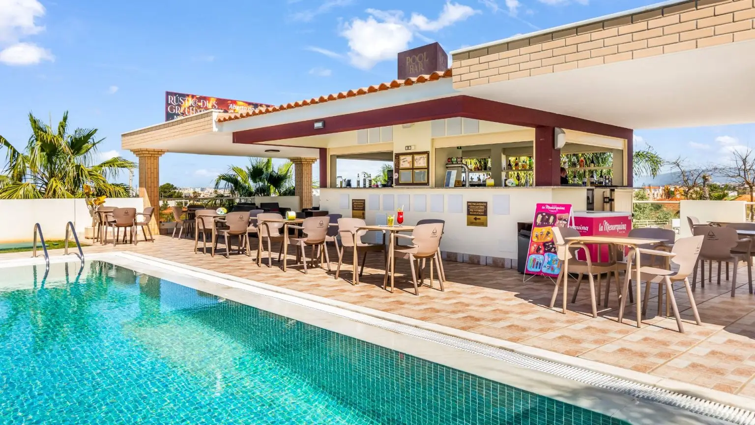 Outdoor poolside bar with chairs and tables under a clear blue sky.