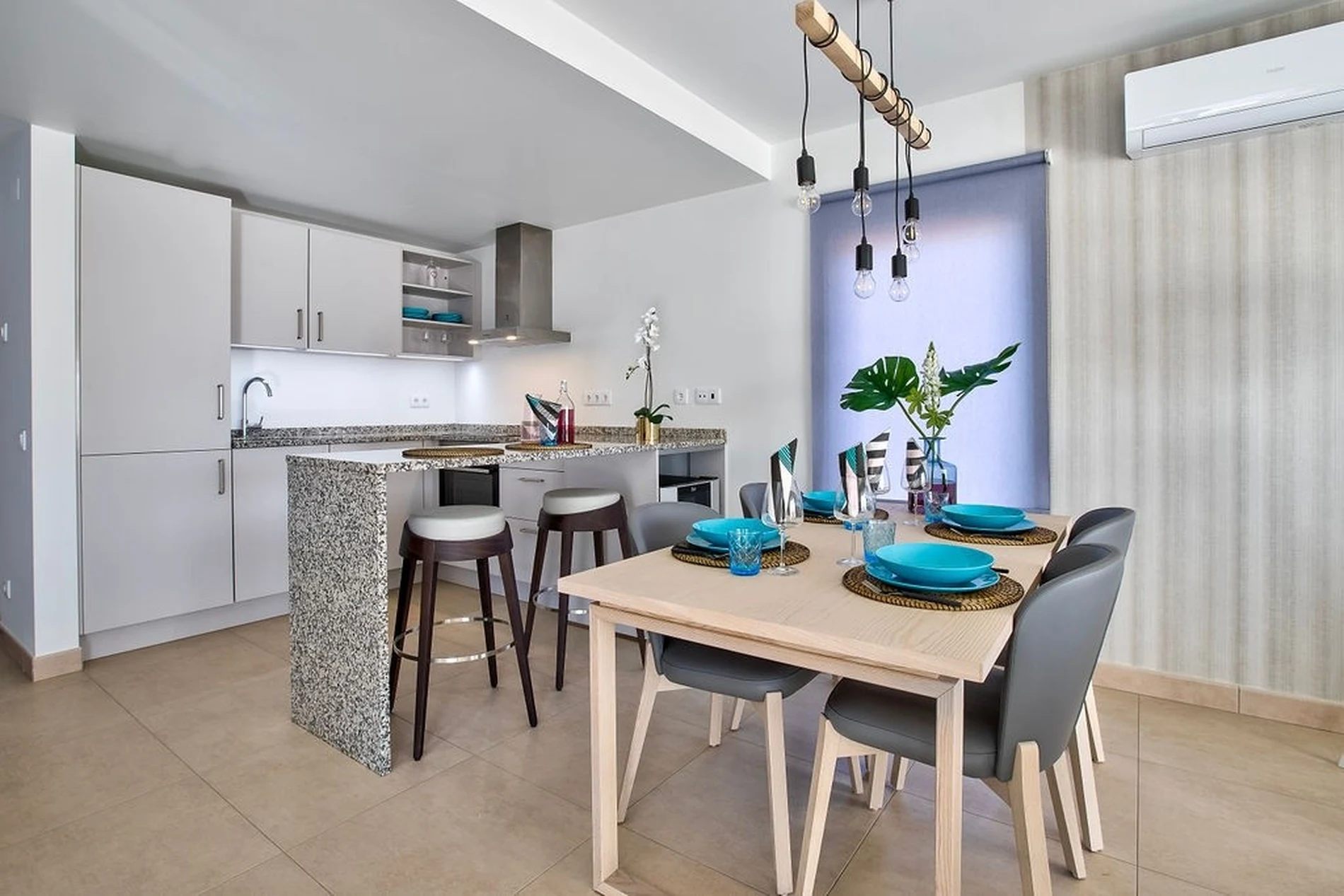Modern kitchen with dining area, bar stools, and pendant lights.