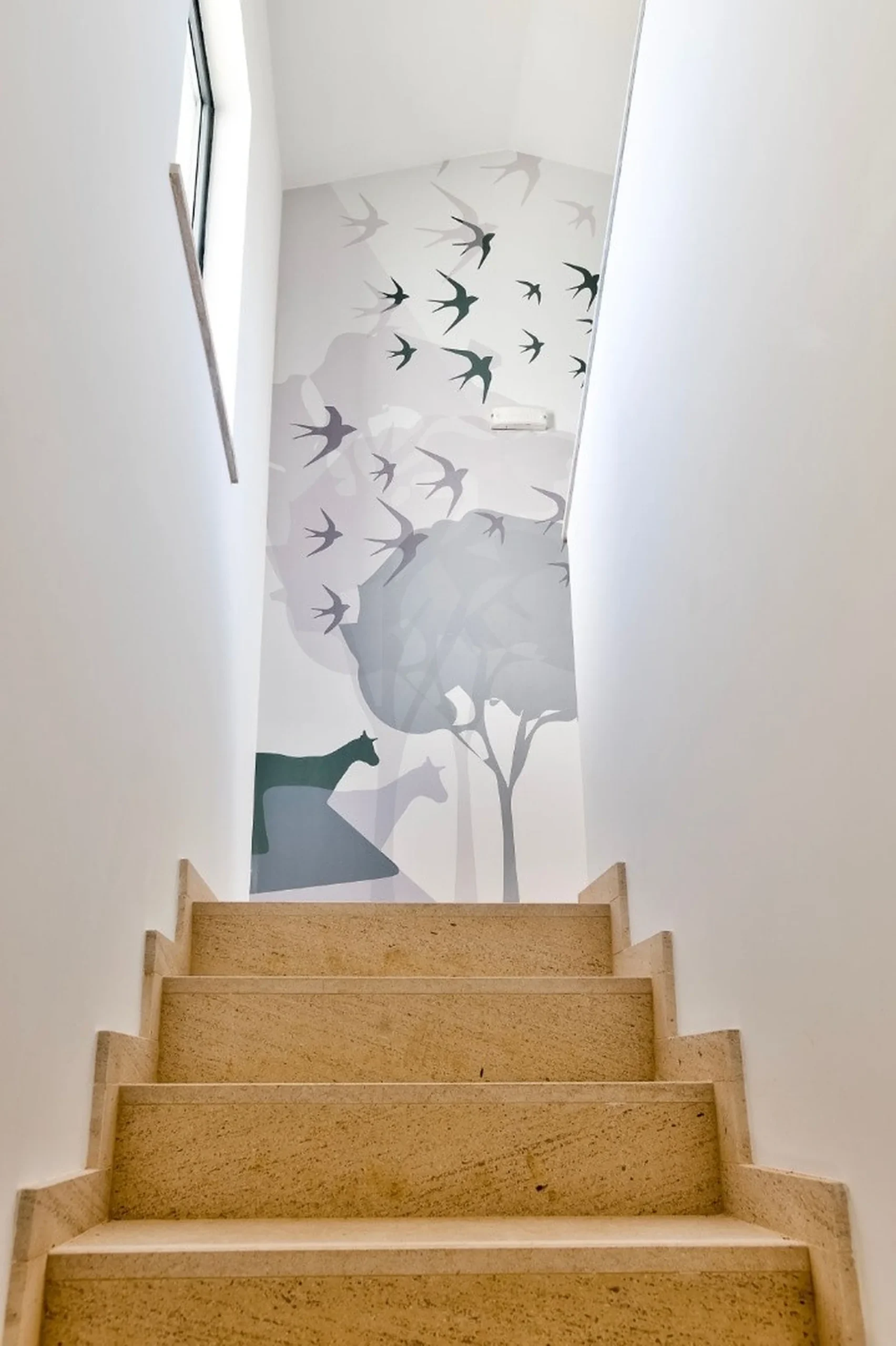 Staircase with mural of birds and trees at the top wall.