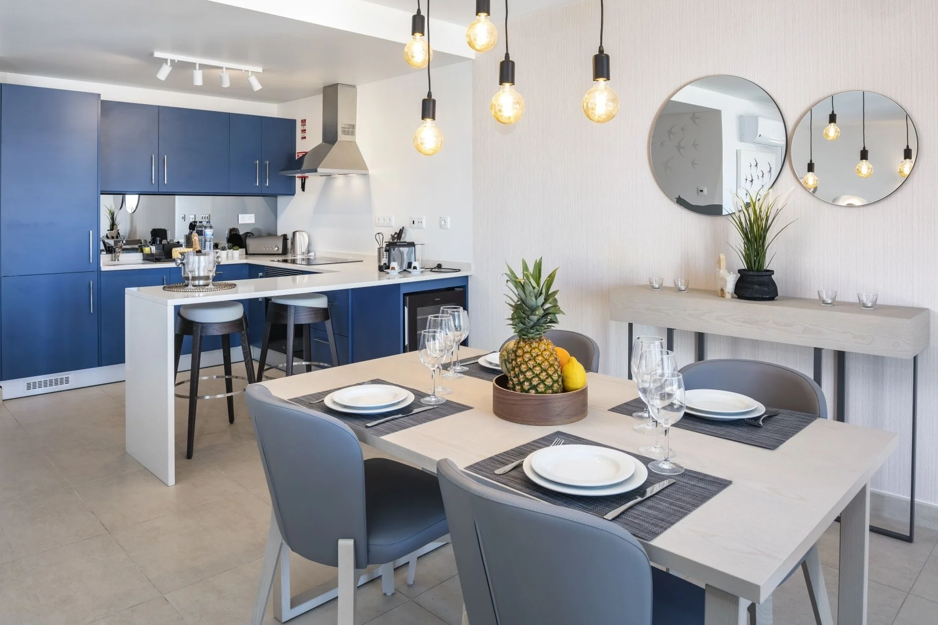 Modern kitchen-dining area with blue cabinets and a fruit centerpiece.